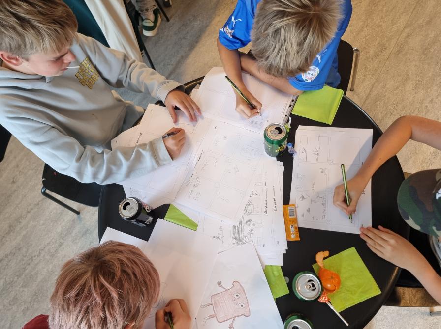 En gruppe drenge sidder og tegner på biblioteket.